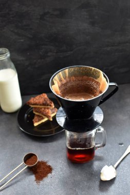 Fındık köşeleri, şeker ve süt dolu koyu bir arka plana karşı filtre torbasından taze buğulanmış kahve.