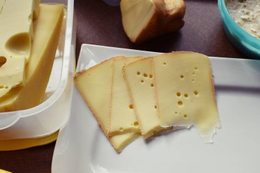 Farklı peynir türleriyle dolu beyaz bir tabak. Almanya 'da akşam yemeği için beyaz bir tabakta dilimlenmiş peynir.