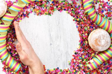 Almanya 'dan gelen karnaval çörekleri, üzerinde konfeti ve flamalar olan hafif ahşap bir yüzeyde krema şekeri ile bir karnaval partisi ya da partiler için arka plan.