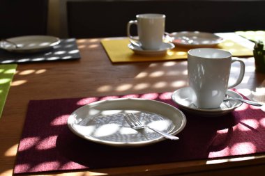 Kahve ve kek için hazırlanmış bir masa üzerinde çatallı bir kek tabağı, bir fincan ve fincan tabağı düz bir arkaplanda - kahve içmek için arka plan ve sıcak bir aile öğleden sonra