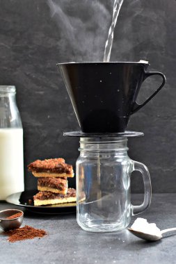 Fındık köşeleri, şeker ve süt dolu koyu bir arka plana karşı filtre torbasından taze buğulanmış kahve.