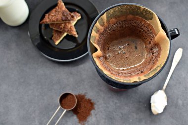 Fındık köşeleri, şeker ve süt dolu koyu bir arka plana karşı filtre torbasından taze buğulanmış kahve.