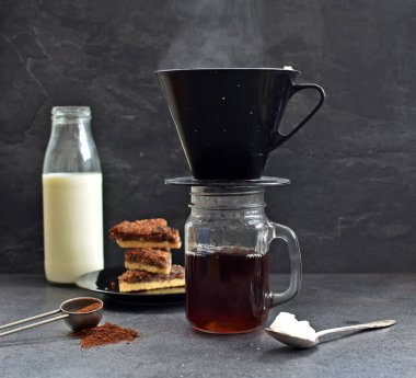 Fındık köşeleri, şeker ve süt dolu koyu bir arka plana karşı filtre torbasından taze buğulanmış kahve.