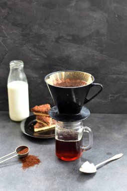 Fındık köşeleri, şeker ve süt dolu koyu bir arka plana karşı filtre torbasından taze buğulanmış kahve.