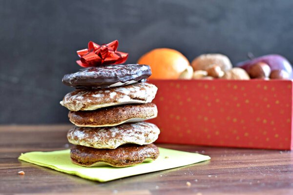 On a bright wooden surface are various types of nuts next to a few delicious German Elisenlebkuchen - German gingerbread on a base as a background