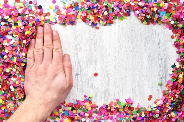 hand frees the surface from the confetti so that the white background is visible