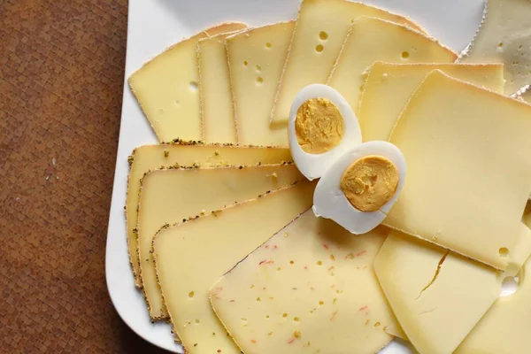 Farklı peynir türleriyle dolu beyaz bir tabak. Almanya 'da akşam yemeği için beyaz bir tabakta dilimlenmiş peynir.