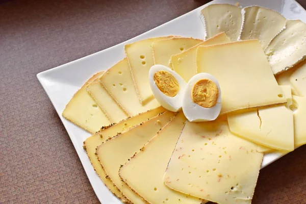 Farklı peynir türleriyle dolu beyaz bir tabak. Almanya 'da akşam yemeği için beyaz bir tabakta dilimlenmiş peynir.