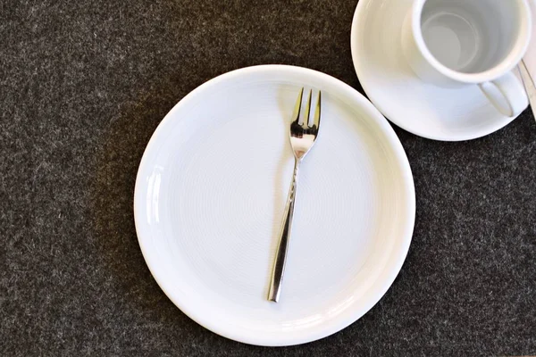 Kahve ve kek için hazırlanmış bir masa üzerinde çatallı bir kek tabağı, bir fincan ve fincan tabağı düz bir arkaplanda - kahve içmek için arka plan ve sıcak bir aile öğleden sonra