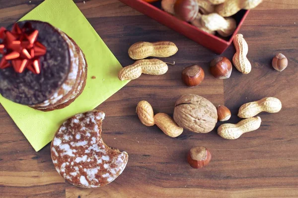 Parlak ahşap bir yüzeyde, birkaç lezzetli Alman Elisenlebkuchen 'in yanında çeşitli fındık türleri vardır. Arka plan olarak Alman zencefilli ekmeği.