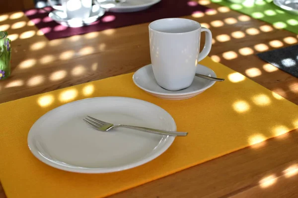 On a table was set for coffee and cake, a cake plate with a fork, a cup and saucer on a plain background - background for drinking coffee and a cosy family afternoon
