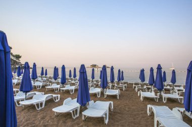 şezlong ve şemsiyeler sabahın erken saatlerinde ıssız bir kumsal.