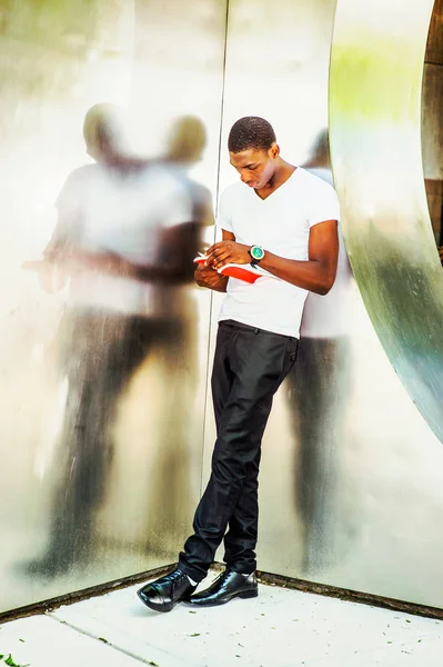 New York'ta dışarıda genç Afro-Amerikan adam okuma kitabı