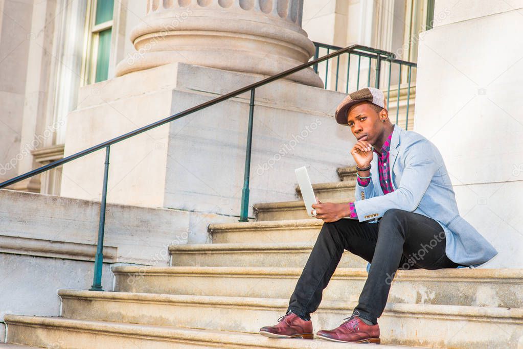 Young African American Man working on laptop computer outside in