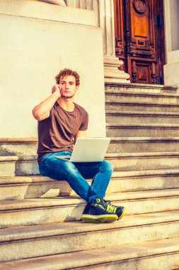 Genç dizüstü bilgisayar üzerinde çalışan erkeğin oturup cep telefonundan sohbet,