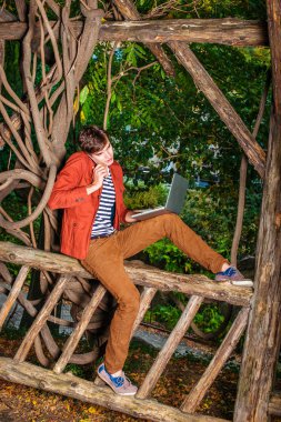 Genç dizüstü bilgisayar üzerinde çalışan C cep telefonuyla konuşan adam