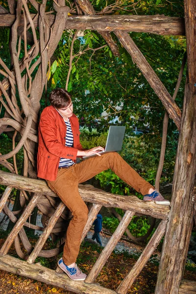 Genç dizüstü bilgisayar üzerinde çalışan C cep telefonuyla konuşan adam