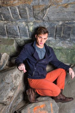 Genç adam kayalar üzerine çömelerek