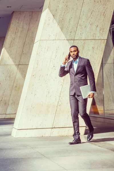 Afrika kökenli Amerikalı işadamı cep telefonuyla konuşurken yürüyüş 