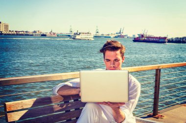 Genç nehir tarafından dizüstü bilgisayarda çalışan adam