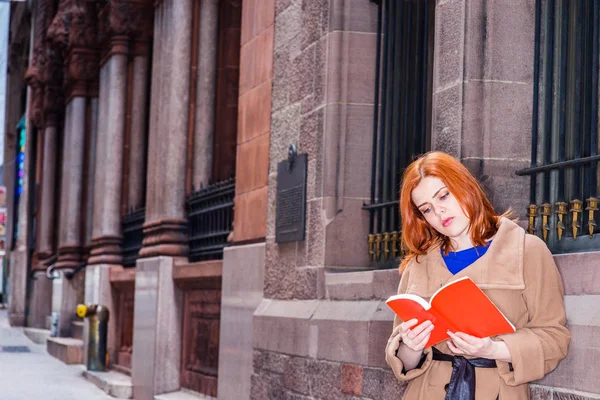 Joven americana leyendo libro rojo al aire libre en Nueva York — Foto de Stock