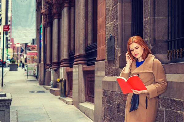 Jonge Amerikaanse vrouw lezen rode Boek, praten op mobiele telefoon uit — Stockfoto