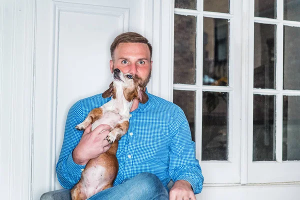 Sakallı, mavi desenli tişörtlü genç bir Amerikalı New York 'ta pencere kenarındaki sandalyede oturuyor bacak bacak üstüne atıyor, Dachshund köpeği tutuyor, dinleniyor. En iyi arkadaşı olan bir adamın portresi.