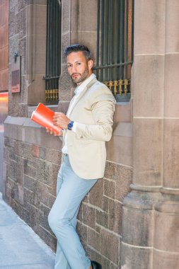 Genç Avrupa kırmızı kitap dışında Manhattan, New York, sakal, küçük gri saç ile okumak, windows, aydınlatma cam içinde duvar tarafından sokakta duran bej ceket, beyaz gömlek giymiş adam