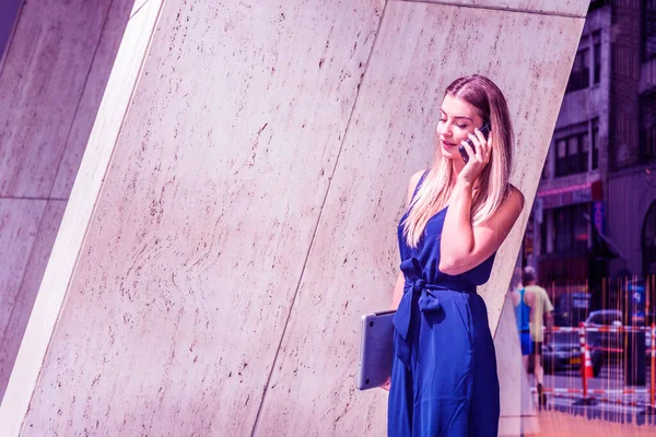 若い東欧のアメリカ人女性電話で話す ニューヨークで働く 青いジャンプスーツを着て ノートパソコンを持って オフィスビルから歩いています カラーフィルター効果 — ストック写真