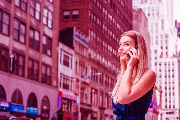 若い東欧のアメリカ人女性が電話で話し 旅行し ニューヨークで働き 青いドレスを着て マンハッタンのミッドタウンに高い建物がある通りを歩いています カラーフィルター効果 — ストック写真