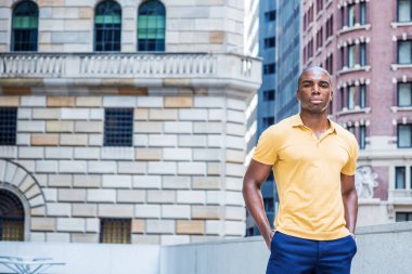 New York 'ta genç Afro-Amerikan erkek sokak modası. Sarı kısa kollu gömlekli, kısa saçlı genç bir üniversite öğrencisi kampüsün dışında duruyor, ileriye bakıyor.