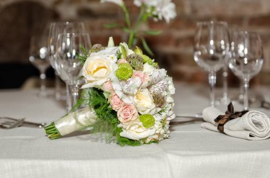 Gelin buketi ve şampanya bardağı masanın üstünde duruyor.