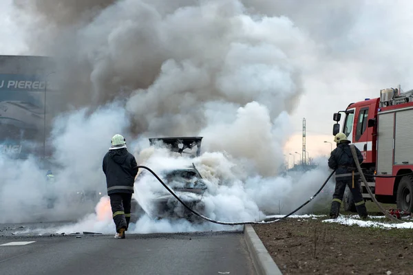 Uns minutos no carro queimado da rua. O trânsito parou. Bombeiros eliminam fogo . — Fotografia de Stock