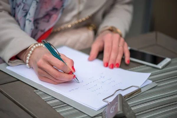 Close-up de mãos femininas. Mulher escrevendo algo sentado no café. Documentos de assinatura . — Fotografia de Stock