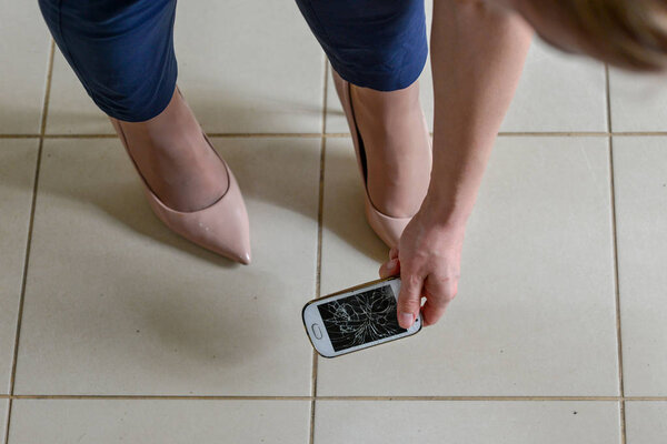 Женщина выбирает сломанный смартфон с треснувшим экраном плитки
.