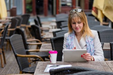 Bir kafede çay içme ve bir bilgisayar ile çalışan bir genç iş kadını. 