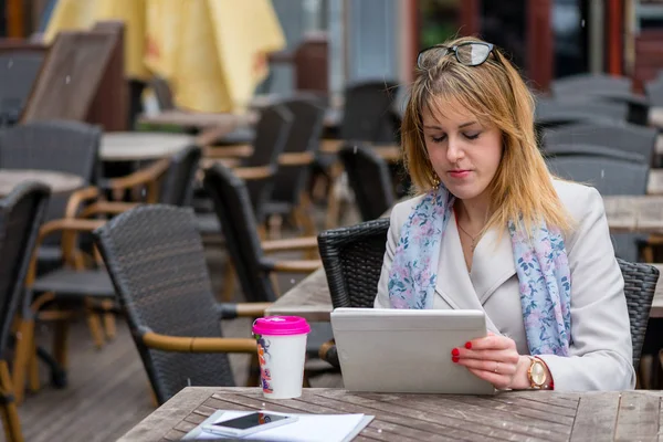 Una joven mujer de negocios bebiendo té en un café y trabajando con un — Foto de Stock