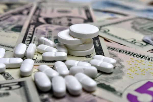 Piller mot bakgrund av de olika nationella sedlarna. Begreppet medicinsk tillgänglighet och ökade sjukvårdskostnader — Stockfoto