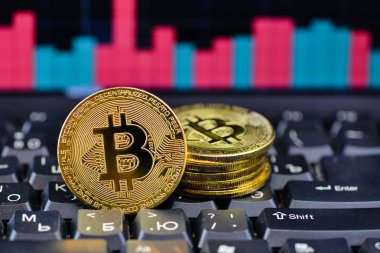 Arkaplanda grafiği olan dizüstü bilgisayarda altın bitcoin, seçici odak