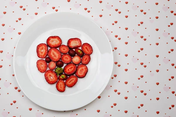 Creative Valentine Day romantic concept composition flat lay top view with heart strawberries on a white plate isolated on a heart  background.