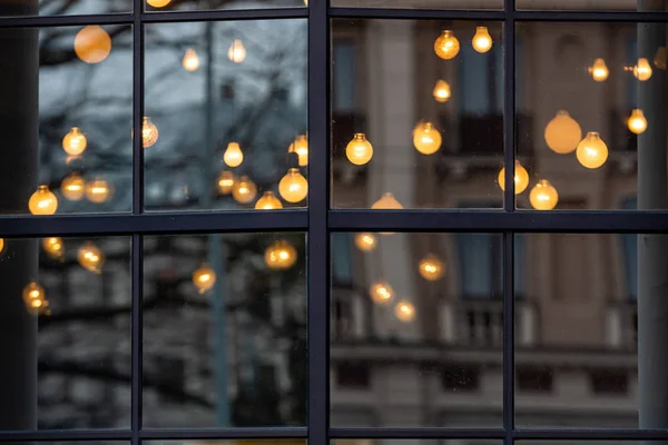 크리스마스 장식용 조명 이 창문을 통해 흐려 지고 도시의 거리가 유리에 반사되고 배경 이 보케 효과로 바뀌다 — 스톡 사진