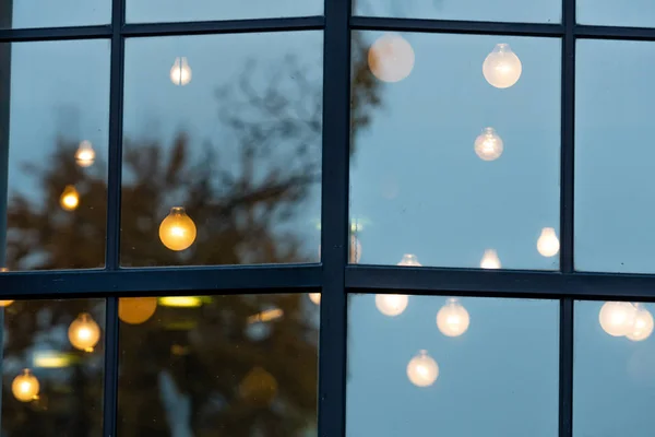 Natal desfocado luzes decorativas de férias através da janela com reflexo de rua da cidade em vidro e efeito bokeh no fundo — Fotografia de Stock