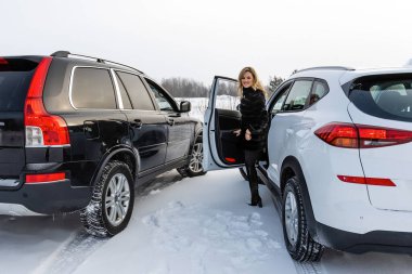 Sarışın kadın beyaz suv arabadan dışarı alır ve geri görünüyor.