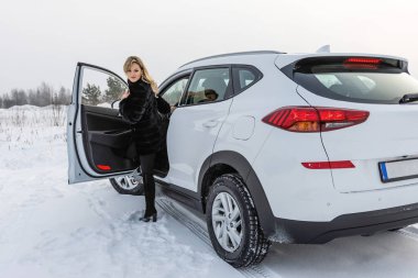 Sarışın kadın beyaz suv arabadan dışarı alır ve geri görünüyor.