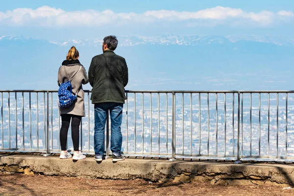 Geneva, Switzerland - April 14, 2019: A couple from the Mont Selave viewing platform look at Geneva and the surrounding area. Rear view — Stock Photo, Image