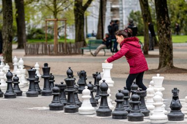 Geneva, Switzerland - April 16, 2019: People playing traditional oversized street chess in Parc des Bastions clipart