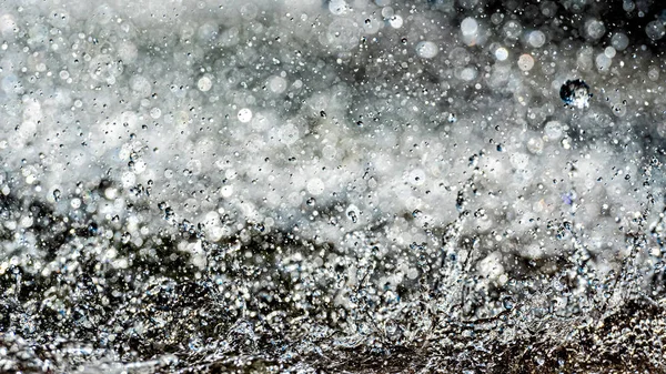 Salpicos de água com pequenas gotas na fonte. Abstrato natural, foco seletivo fundo — Fotografia de Stock