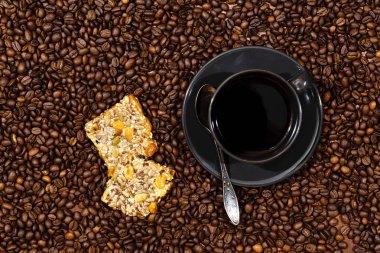 Kahve fincanının en üst görüntüsü ve kahve çekirdekleri arka planında kurabiyeler.