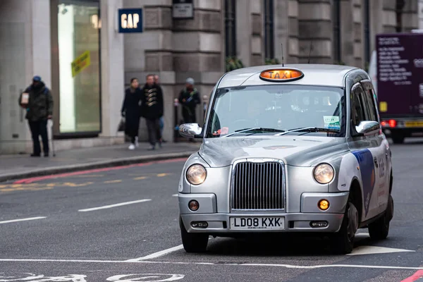 London, England, UK - December 31, 2019:   Typical black London cab in city streets. Traditionally Taxi cabs are all black in London but now produced in various colors — Stock Photo, Image