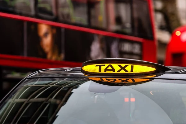 Londyn, Anglia, Uk - 31 grudnia 2019: Brytyjski londyński czarny znak taksówki z nieostrym czerwonym autobusem w tle — Zdjęcie stockowe
